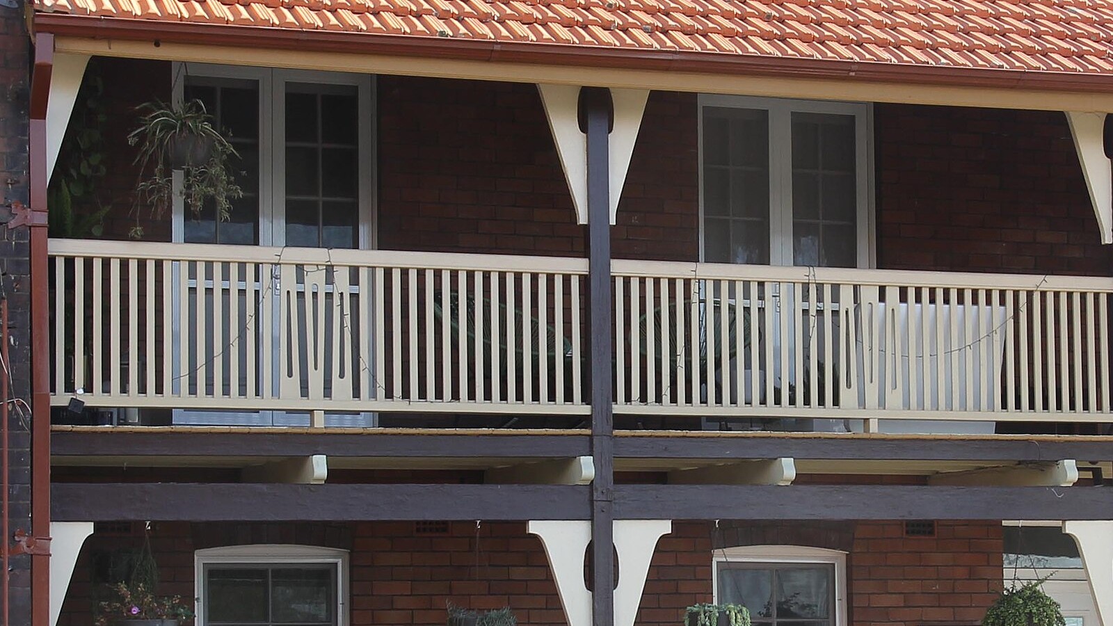 Two-storey brick terraces with lace-trimmed upper verandahs and tiled roofs on an inner Sydney street