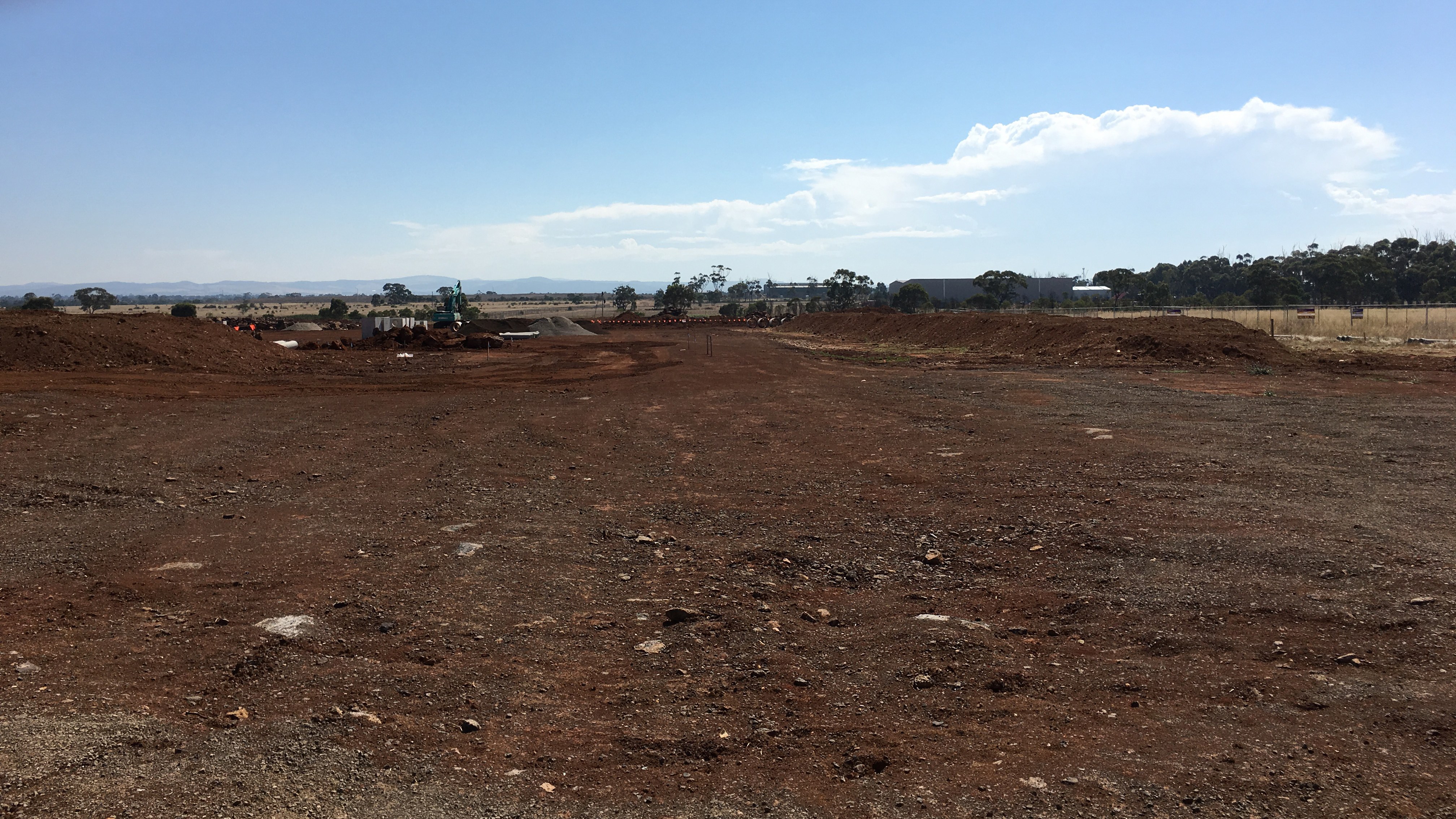Wide view of bare graded land with formed access tracks on a residential subdivision site under a blue sky