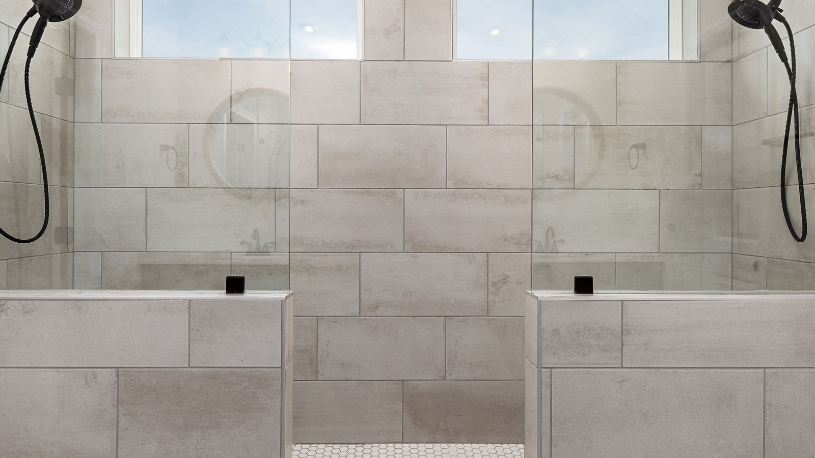 A tiled double shower recess with tiled walls, a tiled upstand and shower heads mounted on opposite sides